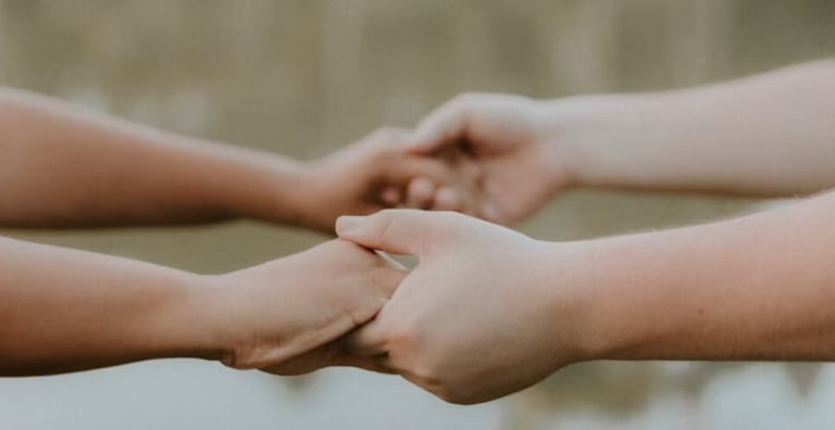 Two hands of two people holding each other