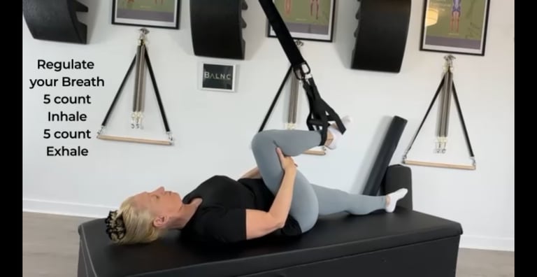 a woman working a yoga pose breathwork as her leg is supported with a suspension trainer