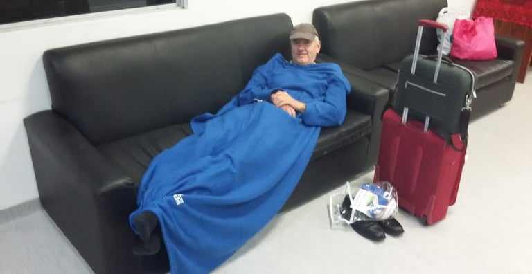 Jörg Grube mit Schirmmütze und Decke auf liegend auf einer Couch