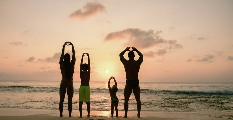Family standing together at sunset on Dreamland Beach Bali enjoying an oceanfront family photography session.