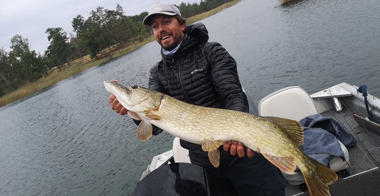 un pêcheur tient un brochet en suede