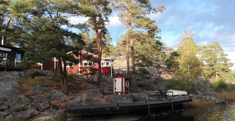 ett svenskt hus ligger vid vattnet för gäddfiske i sverige, det finns träd runt huset.