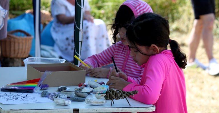 2 children decorating pebbles