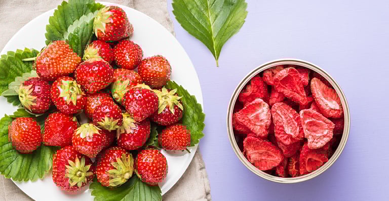 A plate of fresh strawberries and green leaves next to an open container of Thrive freeze-dried food