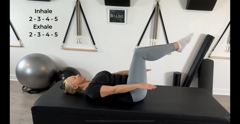 a woman performing Pilates Hundreds exercise