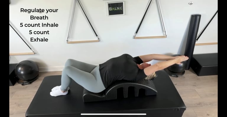 a woman in spine extension on the Pilates Barrel