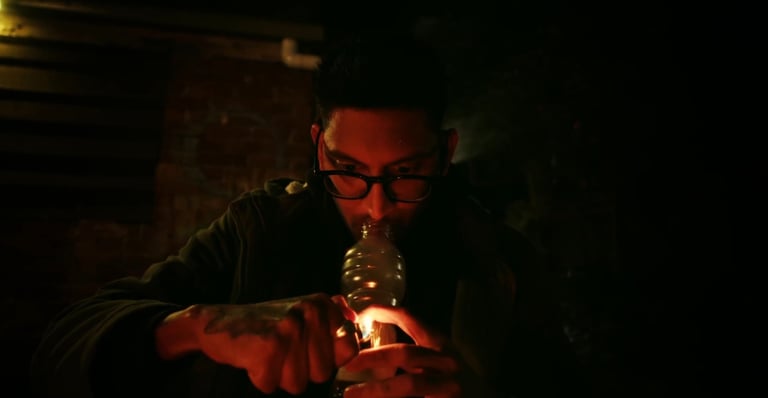 a man in a black jacket is holding a bottle of beer