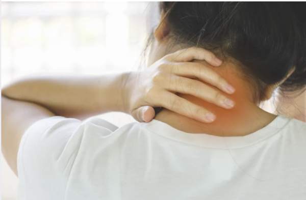 A woman holding her neck in pain, highlighting symptoms of neck strain and cervical spine discomfort.