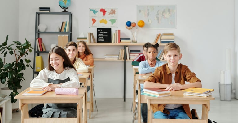a group of teenagers sitting at desks in a classroom