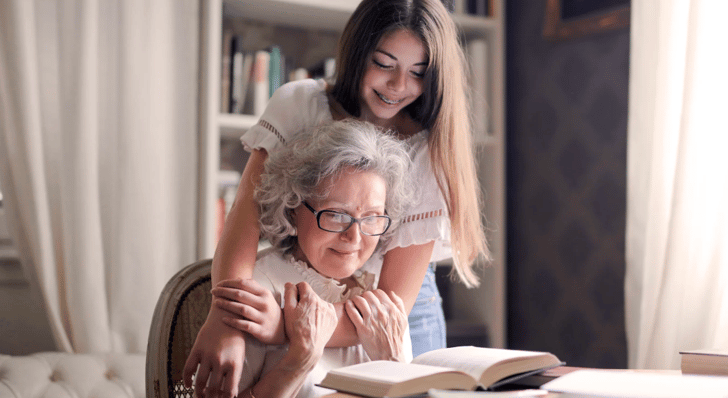 adolescentes qui aide affectueusement une personne âgée lisant un livre
