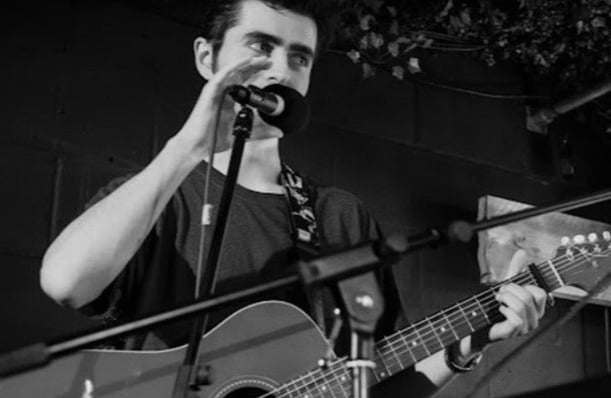Black and white photo of Brighton musician Olly Williams singing and playing guitar