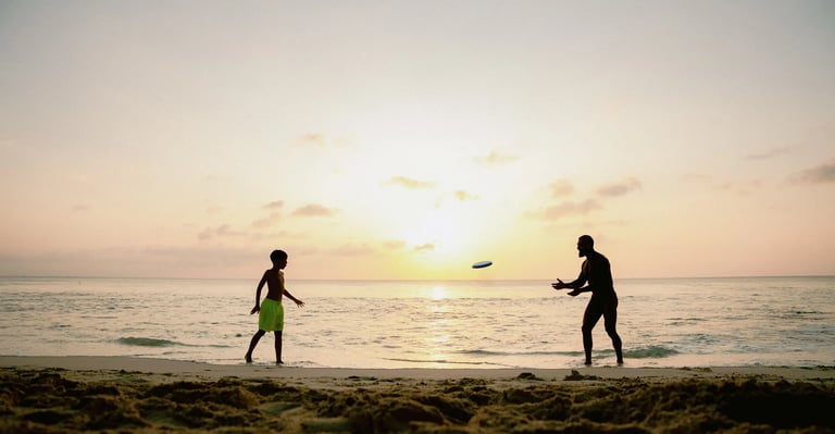 Family enjoying a frisbee game at sunset during a candid beach photography session at Dreamland Beach Bali.