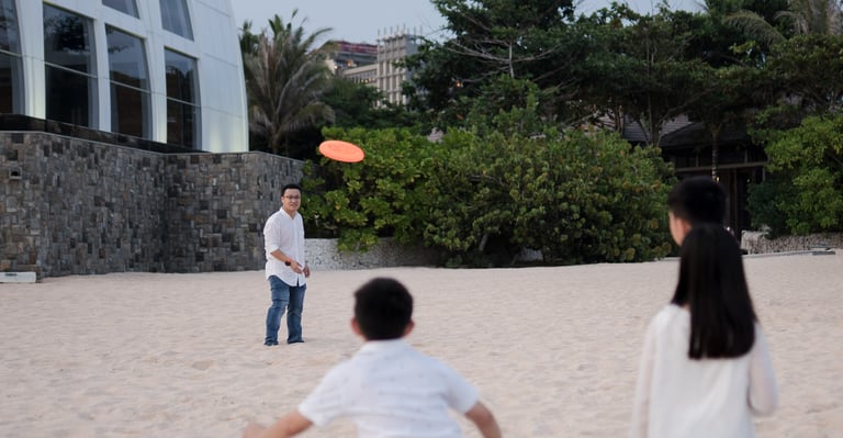 Family enjoying a playful beach moment near the shoreline at The Ritz-Carlton Bali Nusa Dua