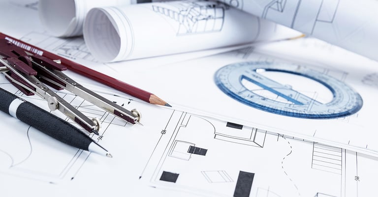 A set of building plans with pen, pencil and a pair of compasses