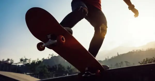 Low angle view of a person performing a skateboard trick at a skate park during a golden hour sunset.