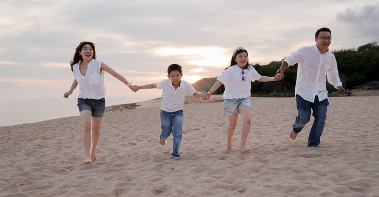 Family running together on the sandy beach during a sunset family photography session at The Ritz-Carlton Bali