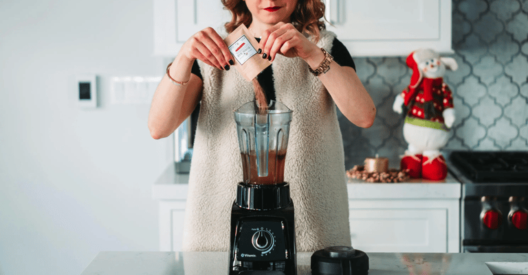 mujer preparando un batido usando una licuadora negra