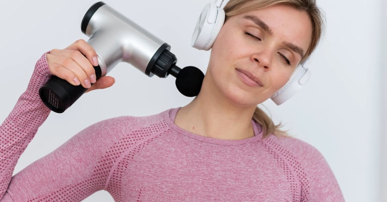 Mujer con camiseta deportiva rosa y audífonos usando un masajeador eléctrico