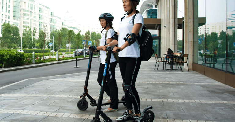dos mujeres usando patinetes electricos en la calle