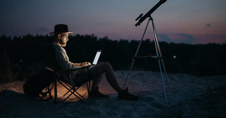 hombre sentado en una silla con una laptop y un telescopio