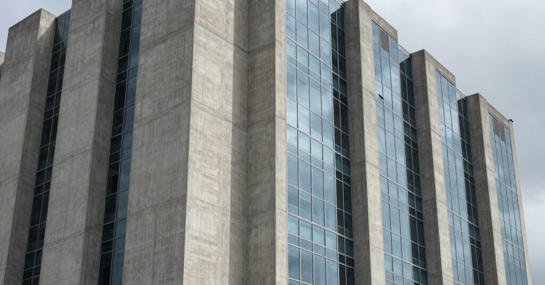 High-contrast architectural shadows on a massive concrete and glass data center facade, overcast sky