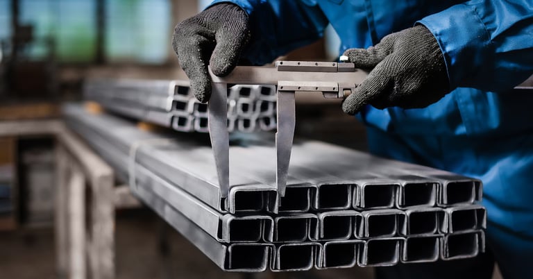 Worker checking the size of rectangular stainless steel pipes
