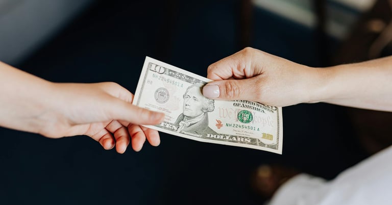 two people holding onto a dollar bill representing gold ira fees and a guide to understanding gold ira fees