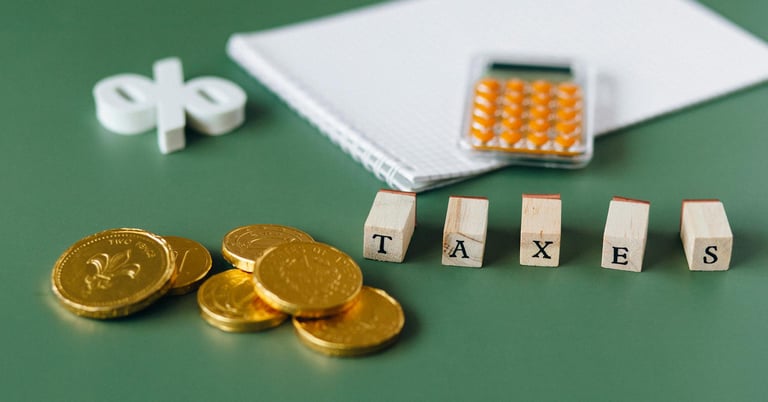 gold coins, calculator and word taxes show gold ira taxes and learning potential tax benefits