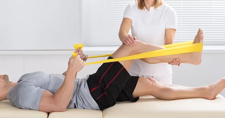 Paciente deitado na maca fazendo exercícios para o joelho usando um elástico