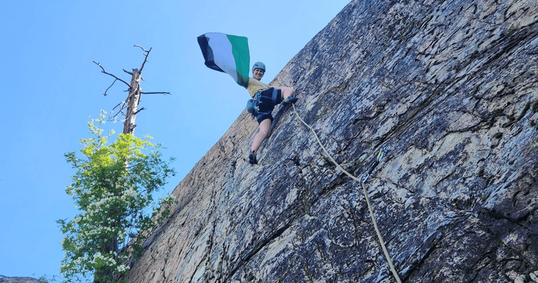 A climber halfway up the wall waving a Palestinian flag