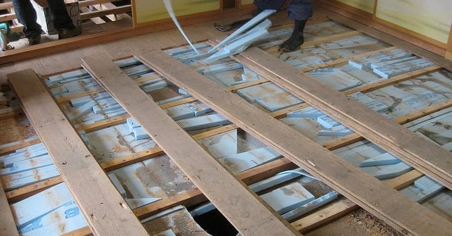 a man standing in a room with a flooring board