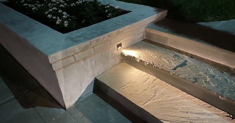 step light recessed in brick landscape planter box shining on a stone step