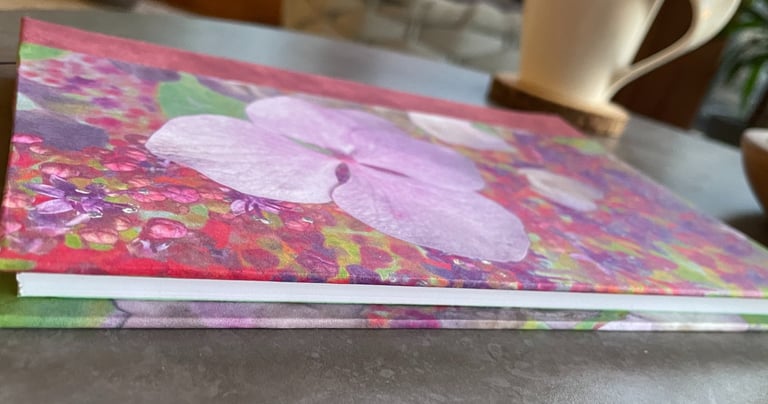 a one of a kind pink and green floral print notebook on a coffee table