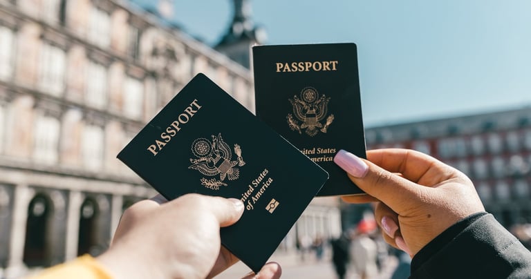 two people holding up two passports in front of a building Super Visa Insurance Quote TWC Financial
