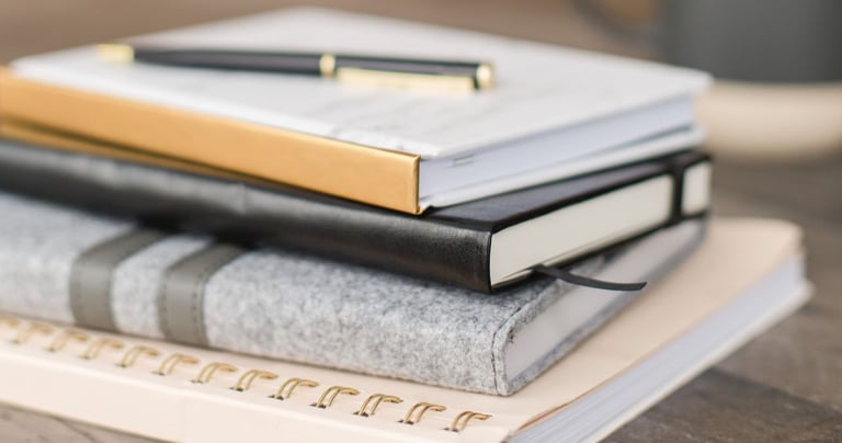 a stack of books and a pen on a table