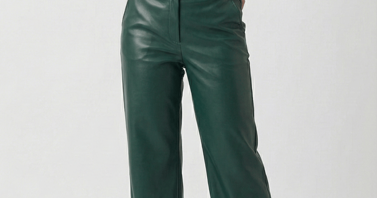 Woman wearing high-waisted dark green faux leather trousers with a cream button-down shirt.