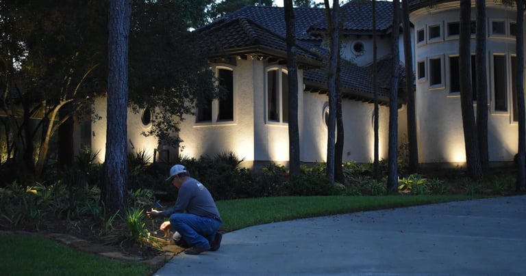 landscape lighting technician servicing a landscape light bulb