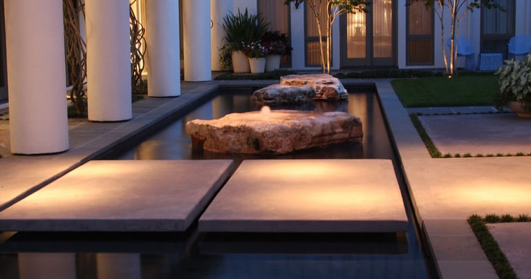 arbor mounted down lights illuminating a path over water fountain