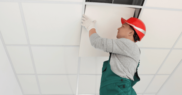 a man in a red hat and overall installing a suspended ceiling