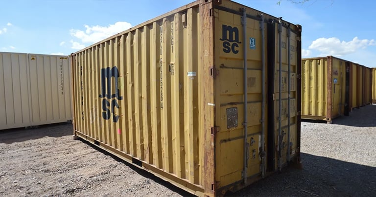 A yellow cargo worthy high cube shipping container with rust dents and dings