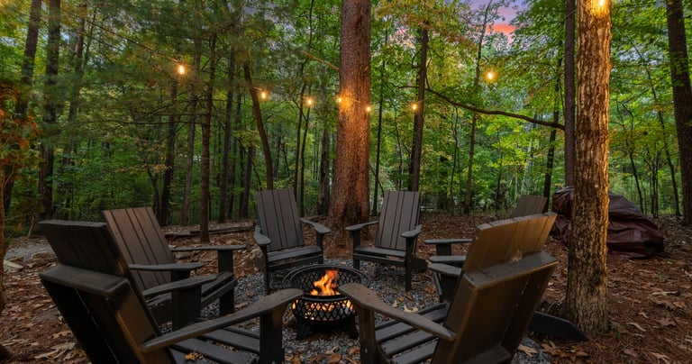 fire pit with chairs under trees with string lights