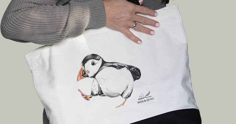 a woman holding a white bag with a puffin bird on it