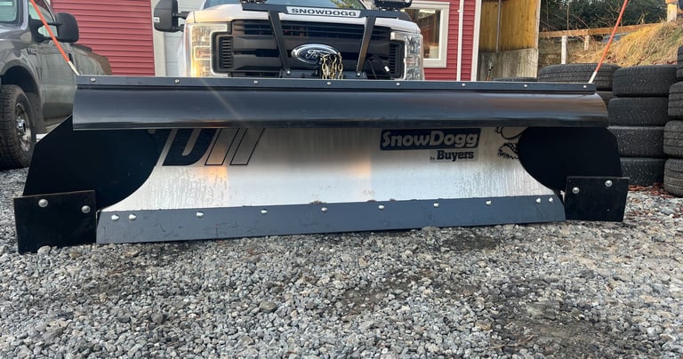 picture of the front of a white truck with a silver plow blade on it