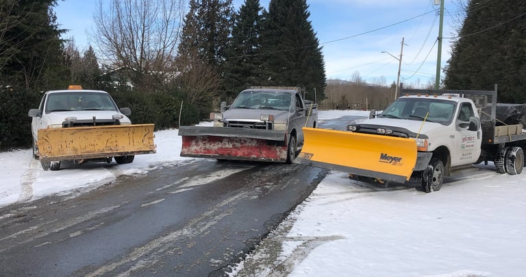 three plow trucks parked beside each other