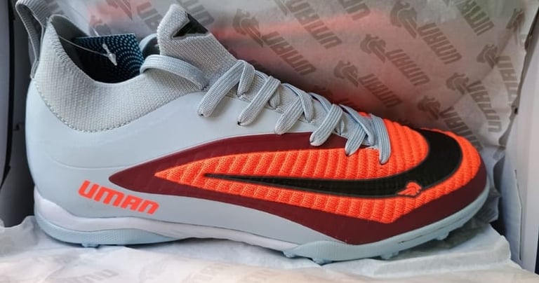 Zapatos de fútbol para césped artificial Uman en gris y naranja para superficies.