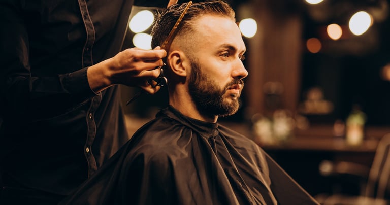 Professional barber giving a stylish fade haircut to a bearded man in a vintage barbershop.