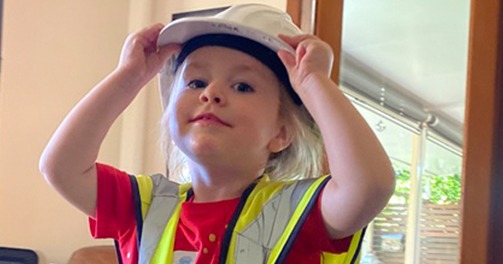 A young future construction boss in a safety helmet