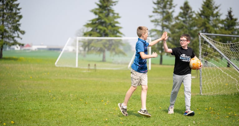 two boys playing soccer in a field
