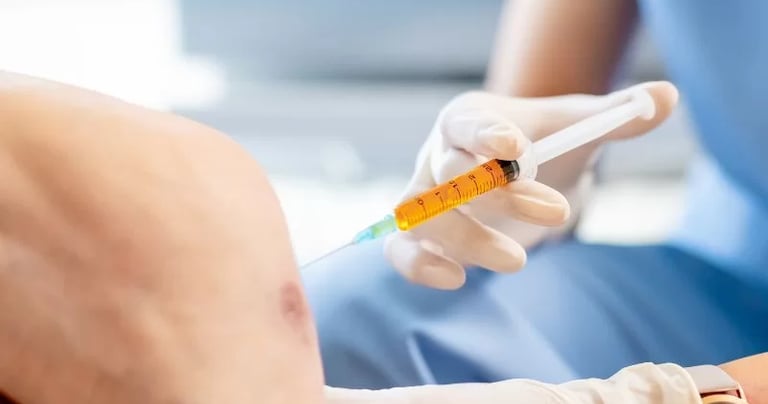 A healthcare professional administering a knee joint injection for arthritis pain relief treatment.