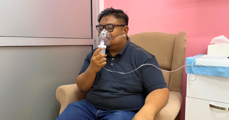 A man using a medical nebulizer mask for respiratory treatment in a clinic setting.